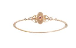 8.  Pulsera rígida S. XIX con motivo central oval, con rubí en marco romboidal, y volutas decoradas con perlas