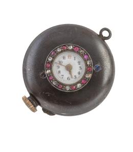 69.  Reloj de pp. S.XX con pequeña caja circular orlada de rubíes y diamantes, con caja de maquinaria en metal pavonado