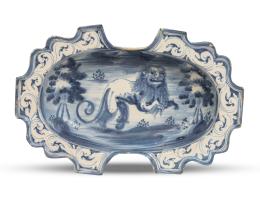 1080.  Bacía de doble escotadura de cerámica esmalttada en azul y blanco con león rampante en el asiento y cenefa de hojas.Talavera, S. XVIII.