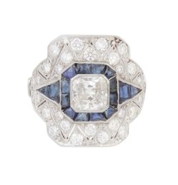 389.  Sortija estilo Art-Decó con diamante talla princesa central de 1,50 ct, sobre marco cuadrado de zafiros flanquedo por triángulos y marco exterior cuajado de brillantes