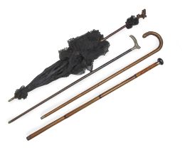 1185.  Conjunto de una sombrilla de madera con seda negra con flores y encaje y tres bastones de madera, uno rematado por mango de metal con flores.Finales del S. XIX - principios del S. XX.