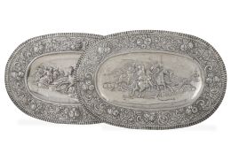 1384.  Pareja de bandejas de plata repujada con escenas de batalla y perímetro con frutos.S. XIX.