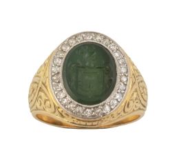196.  Sortija sello de pp. S. XX, con intaglio de escudo familiar en piedra verde, con marco oval de brillantes, en montura ancha con decoración labrada