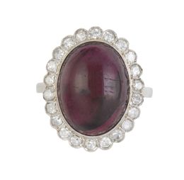 324.  Sortija c.1930 con cabuchón de granate orlada de brillantes en marco ondulado