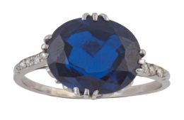 150.  Sortija con zafiro sintético central en talla oval, con diamantes en los brazos de la montura