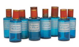 671.  Conjunto de nueve botes de farmacia de cristal azul con tapones de metal en rojo y dorados.Principios del S. XX.