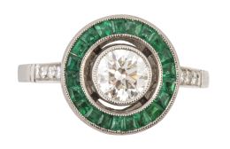 305.  Sortija ojo de perdiz con brillante central de 0,60 ct.orlado de esmeraldas calibradas, con tríos de brillantes decorando los brazos de la montura