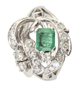 202.  Sortija años 60 de diseño asimétrico, con esmeralda engastada en garras rodeada de cintas y ramita con brillantes