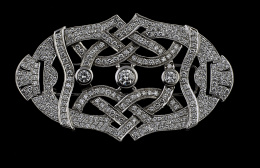551.  Broche placa de brillantes de estilo Art-Decó con diseño de cintas entrelazadas, con tres centros que suman 1,10 ct