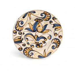 900.  Plato de cerámica esmaltada de la serie tricolor con una flor en el asiento y hojas en el alero.Talavera, S. XVII