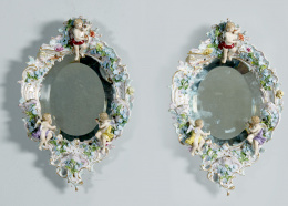 492.  Pareja de espejos de porcelana esmaltada con “putti” aplicados y flores.Alemania, h. 1900..