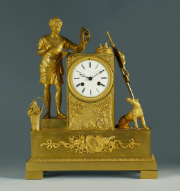 971.  Reloj de sobremesa de bronce dorado con la figura mitológica sobre sobre plinto ..Trabajo francés primer cuarto del S. XIX.