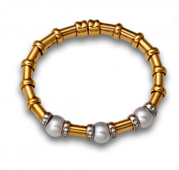 127.  Brazalete flexible con tres perlas australianas de 11 mm entre bandas de brillantes .En oro liso de 18K con decoración de aros en relieve .