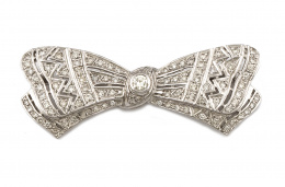 603.  Broche lazo de brillantes en oro blanco de 18K con líneas caladas y centro de chatón de 0,30 ct.