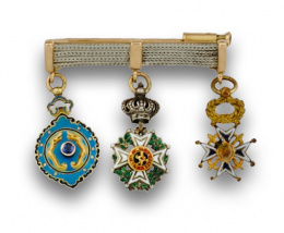 656.  Broche en oro de 18K y platino con tres insignias militares de plata dorada y esmalte