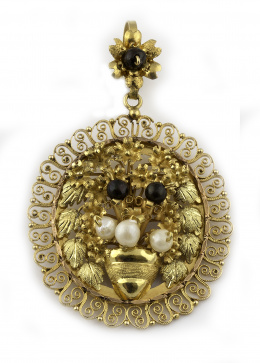 82.  Colgante oval mexicano en oro de 14 K. con centro floral adornado con perlitas blancas y negras, enmarcado con filigrana