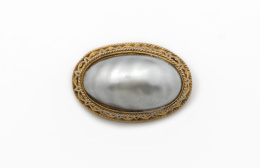666.  Broche de gran perla mabe gris con marco en metal dorado.