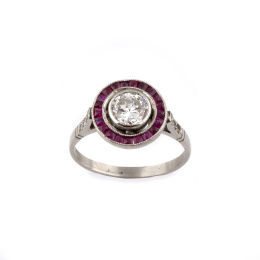 694.  Sortija ojo de perdiz con un brillante en chatón central de 0,62 ct orlado de rubíes calibrados.
