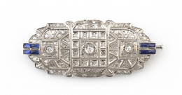 689.  Broche placa Art Decó diseño geométrico con tres chatones de brillantes y diamantes y a los lados dobles bandas de zafiros calibrados