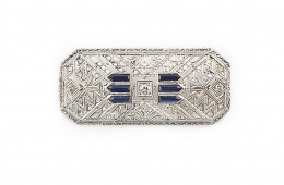 447.  Broche placa Art-Decó de brillantes y diamantes con tres bandas de zafiros a cada lado del brillante central