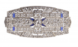 105.  Broche placa Art-Decó con cinco brillantes centrales en chatones  de tamaño creciente hacia el centro y  zafiros calibrados en los extremos y aspas centrales