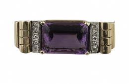 294.  Broche años 30 con amatista rectangular entre bandas de brillantes y arcos con base de galería calada. En oro rosa de 18K