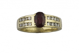 739.  Sortija con rubí de talla oval flanqueado por dobles bandas de brillantes engastados en carril, en oro amarillo de 18K