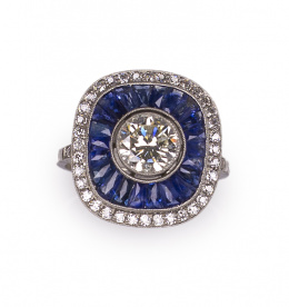 607.  Sortija estilo Art-Decó con brillante central de 1,5 ct rodeada de zafiros calibrados y brillantes en orla exterior