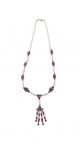 761.  Collar de brillantes y cabuchones de rubíes, con centro a modo de borla colgante y cuerpo del collar formado por rivière de chatones adornada por nueve motivos de racimos de cabuchones de rubí. 