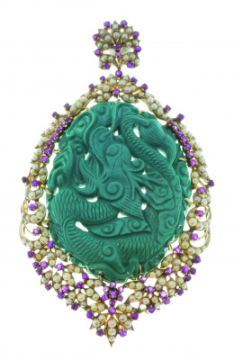 667.  Colgante oriental con gran turquesa ovalada tallada con formas de dragón rodeada por un marco de rubíes y perlas finas que componen formas vegetales.