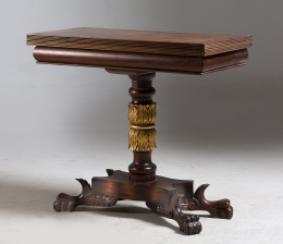 1198.  Mesa de juego estilo imperio en madera de caoba y policromada en oro sobre pedestal con patas de garra.S. XX..