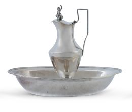 1223.  Jofaina y aguamanil Carlos IV de plata rematado en la tapa con hombre con jarra y copa sentado sobre barril. Con marcas.Jofaina con marcas de Córdoba, Diego de la Vega, h. 1806.Jarro de plata en su color, marcado JGZ, pp. del S. XIX.
