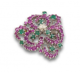 142.  Broche flor años 60 de rubíes y esmeraldas, con centro de brillante de 0,50 ctes aprox. En oro blanco de 18K.