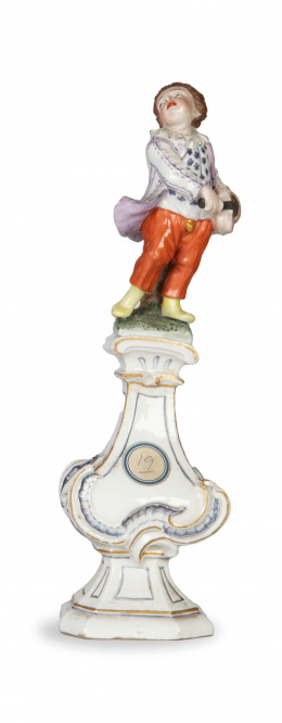 1294.  Niño con instrumento sobre columna.Figura de porcelana esmaltada y dorada.Alemania, S. XVIII.