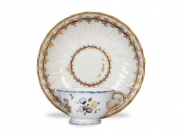 1313.  Lote de taza de loza esmaltada y dorada y plato de porcelana. Ambos con marcas.La taza de Veuve Perrin, Marsella, (1740 - 1803).Plato de porcelana esmaltada en azul y dorada alemana, S. XVIII.