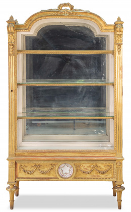 1288.  Vitrina estilo Luis XVI de madera tallada y dorada, con un plato de porcelana francesa inserto en la base. Francia, h. 1900.