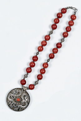 791.  Collar de cuentas de coral manzana y medallón central de plata con dragones grabados.