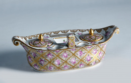 1213.  Escribanía estilo imperio con forma de góndola, siguiendo modelos de Sévres en porcelana dorada y esmaltada con rosas dentro de una retícula.Samson, S. XIX.