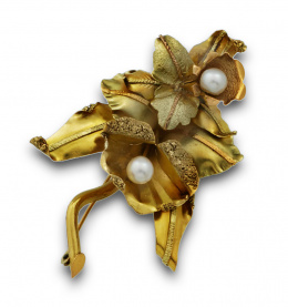 611.  Broche naturalista en forma de orquídeas; realizado en lámina de oro de 18K con decoración grabada y aplicada y perlas centrales.