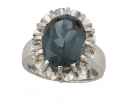 58.  Sortija con fluorita azul de talla oval con marco ondulado en montura de oro blanco de 18K.