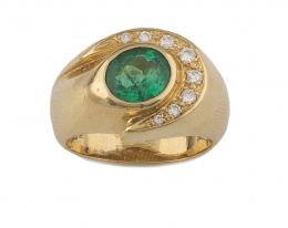 181.  Sortija con esmeralda oval rodeada por onda de brillantes, en montura de oro amarillo de 18K.