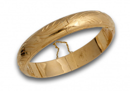 77.  Bazalete rígido en oro de 18K con decoración grabada. 