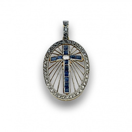 709.  Colgante pps s. XX con cruz de zafiros calibrados en marco oval de diamantes. 