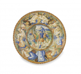 1163.  Plato de cerámica esmaltada con escena de batalla y “putti” en el alero.Italia, S. XVI.