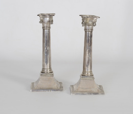 1049.  Pareja de candeleros de plata en su color con forma de columna, rematada por cabezas de carneros. Con marcas BSL y TAF.Bilbao, S. XVIII - XIX..