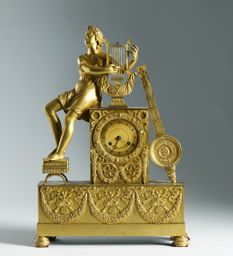 1135.  Reloj de bronce dorado, con la figura escultórica de Apolo apoyado sobre la esfera y el plinto.Francia mediados del S. XIX