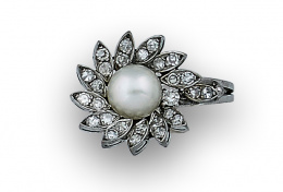 147.  Sortija flor con perla y orla de brillantes en pétalos con diseño elevado hacia un lado. En oro blanco de 18K.