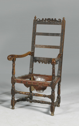 1186.  Butaca tallada de madera de nogal.Trabajo español, de ff. del S. XVII.