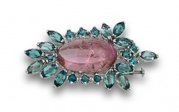 33.  Broche con cabuchón de turmalina rosa y topacios azules en montura de oro blanco de 18K.