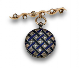 540.  Colgante guardapelo circular s.XIX que pende de broche con perlitas. En oro de 18K.